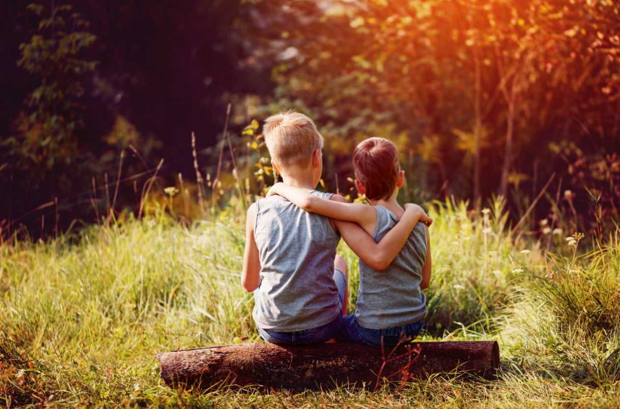 two boys sitting on a log in the forest Christina Vaillancourt Registered Psychologist