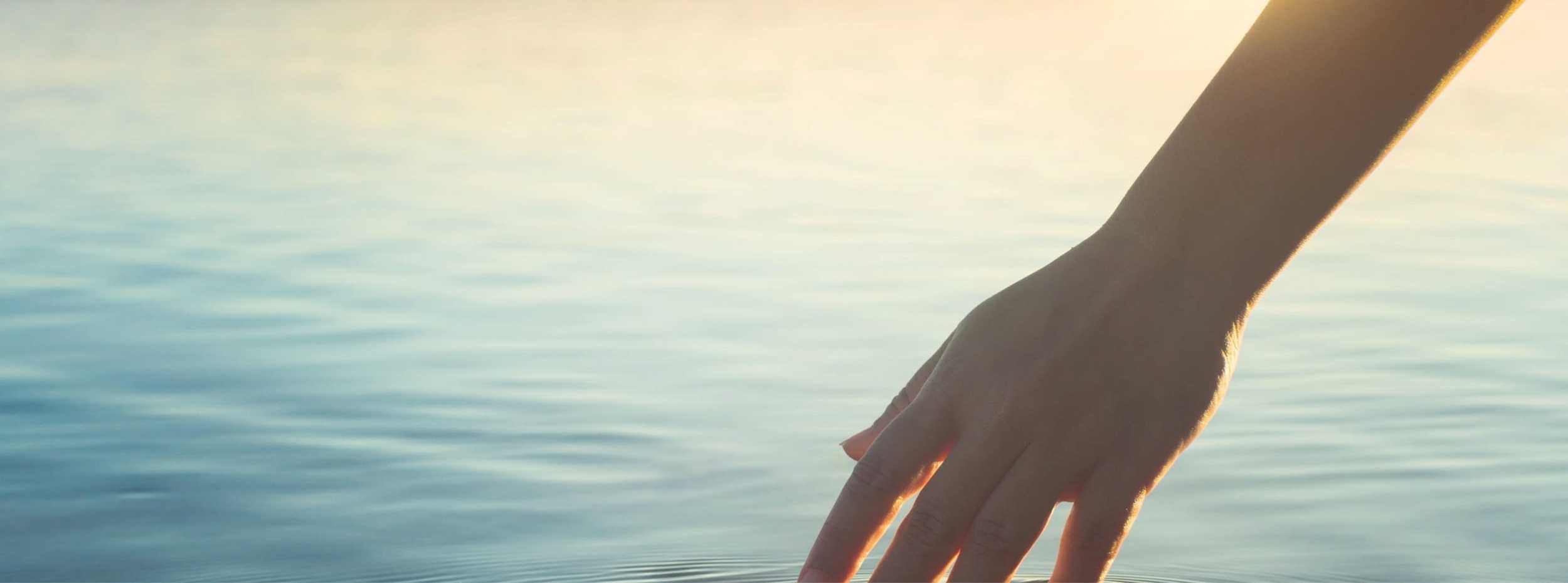 a hand touching a lake Christina Vaillancourt Registered Psychologist
